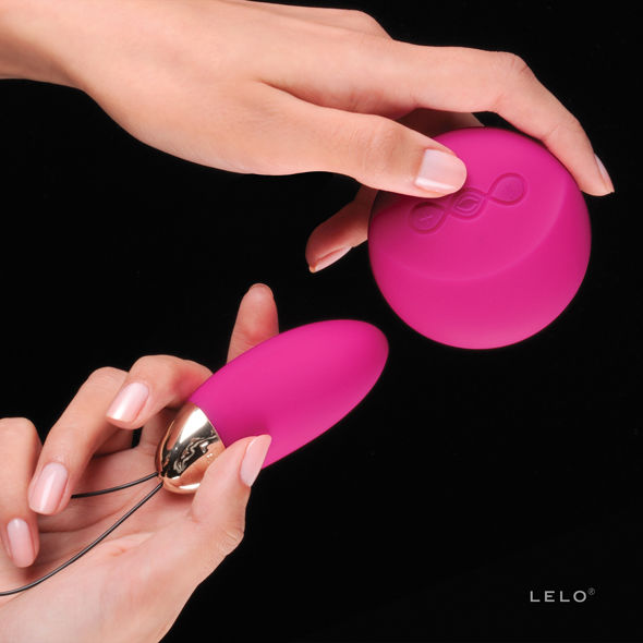 Detalhe do LELO Lyla 2 Insignia Oval Massageador em cor cerise com o seu controlo remoto, destacando o design elegante e a tecnologia SenseMotion™.